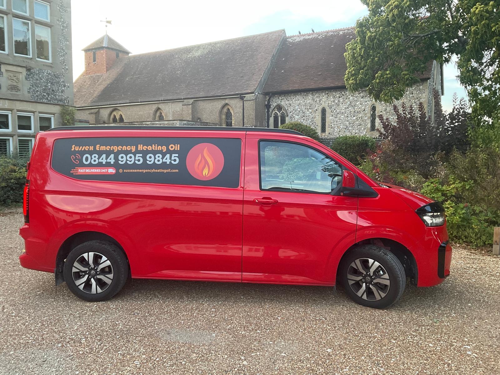 Sussex Emergency Heating Oil delivery van parked beside a church
